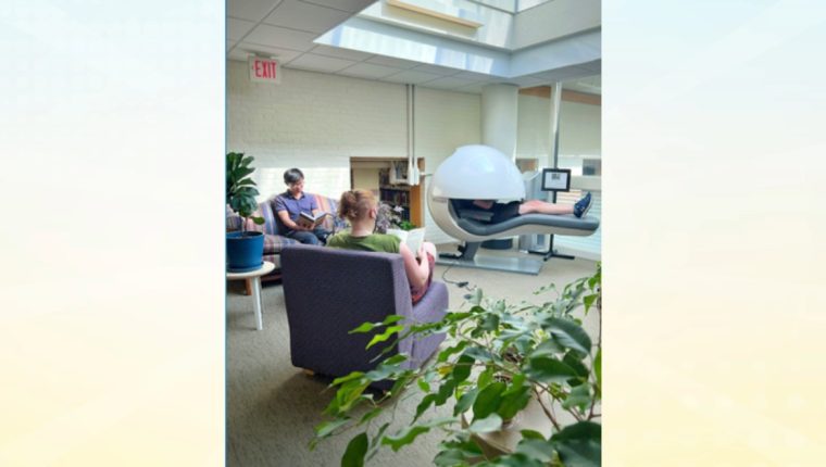 various people relax in the reading garden, nap pod, and couches next to plants.